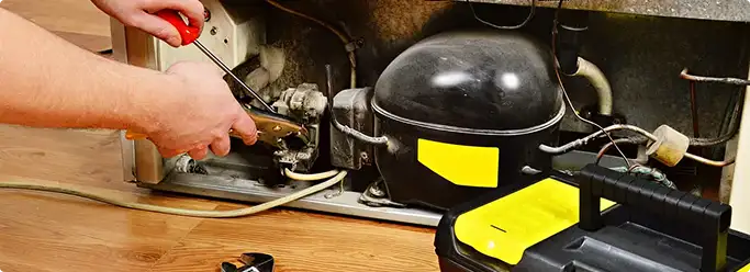 Refrigerator repair technician fixing the compressor and wiring in Demarest, NJ