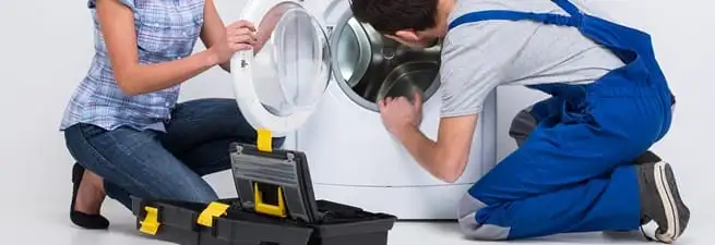 Washer repair technician inspecting a front-load washing machine with tools in Yonkers, NY