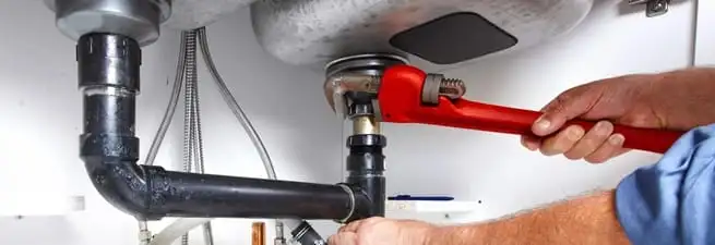 Garbage disposal repair technician tightening the sink drain and disposal connection in Yonkers, NY
