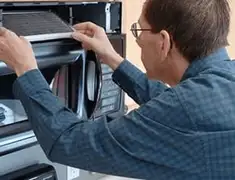 Appliance repair technician replacing a microwave vent filter in Yonkers, NY