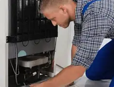 Refrigerator repair technician servicing the compressor and condenser area in Yonkers, NY
