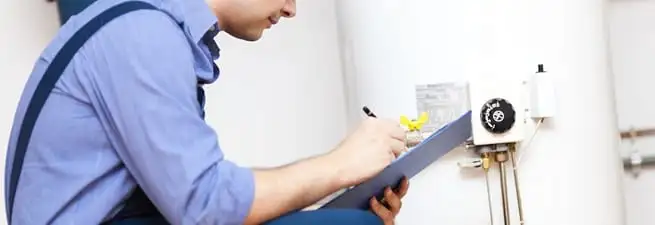 Water heater repair technician inspecting the unit and recording service notes in Yonkers, NY