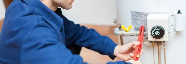 Water heater repair technician adjusting the temperature control and gas valve in Yonkers, NY